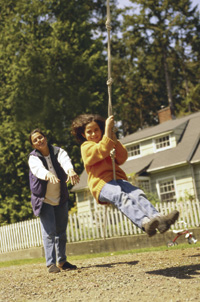 Mother pushing daughter on swing