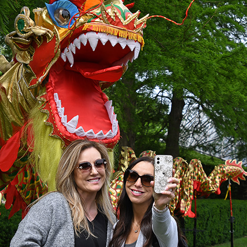 Women pose for a photo in front of a traditional Chinese dragon costume