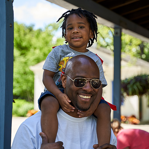 Man in sunglasses with young boy on his shoulders