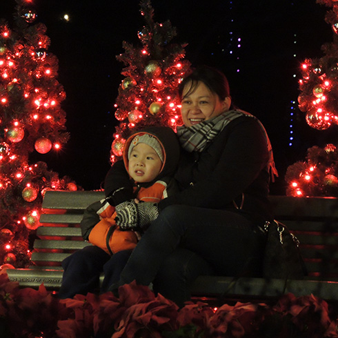 Adult with child on bench surrounded by warm red lights