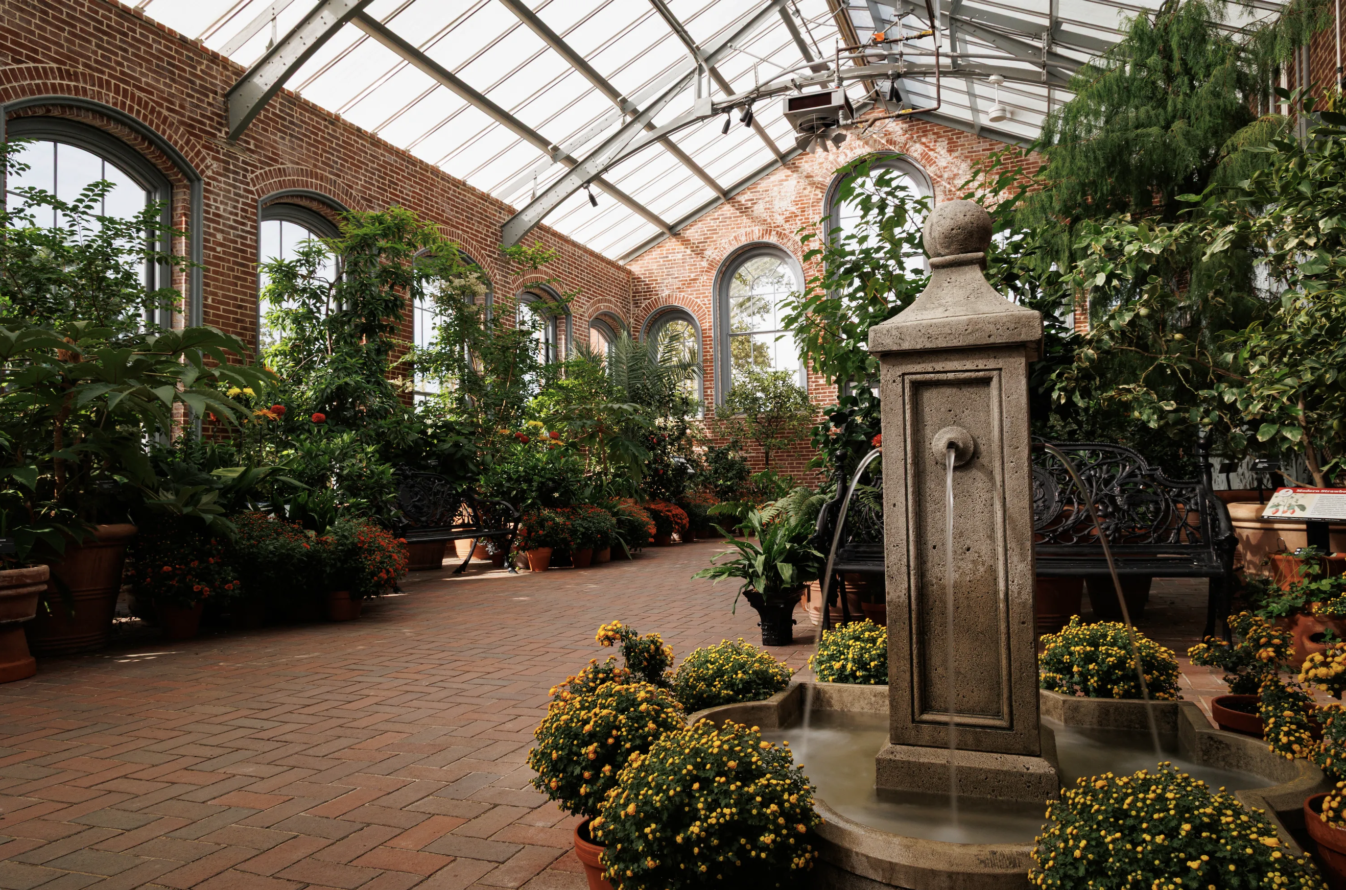 brick conservatory interior with stone fountain and potted trees