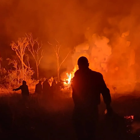 figures in foreground silhouetted by orange fire in background