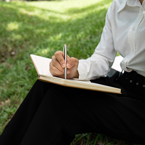 Person writing in garden space