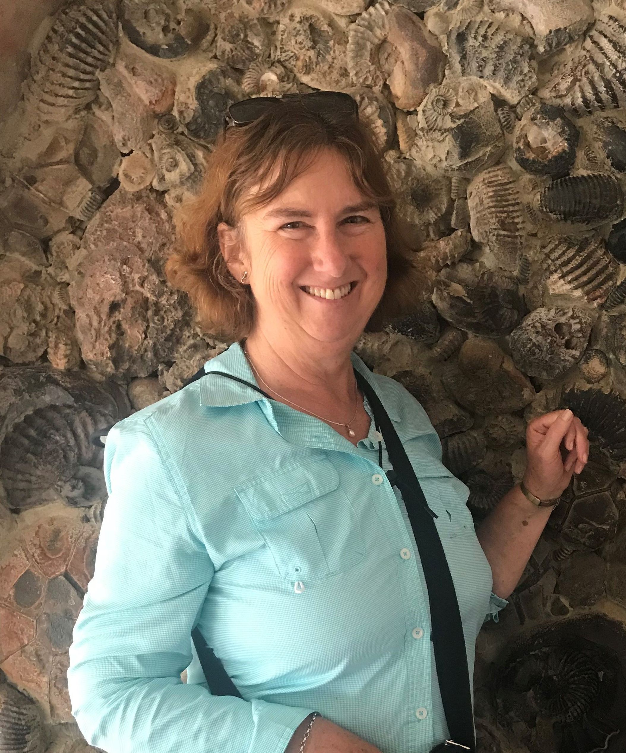 Portrait of Diane Wyse Jackson standing in front of a wall of fossils