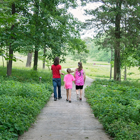 adult and two children walking trail into an open vista