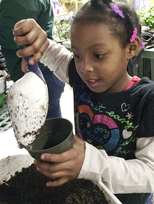 Girl filling pot with soil