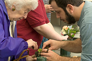 Hortucultural therapist helping a senior pot a plant