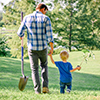 Man and boy walking with tree seedling and shovel